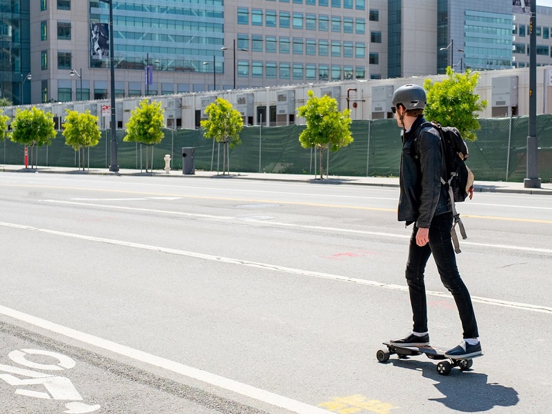 man riding an electric skateboard on the street