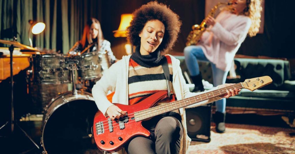 woman playing electric bass guitar with band