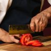 person cutting a tomato with nakiri kitchen knife