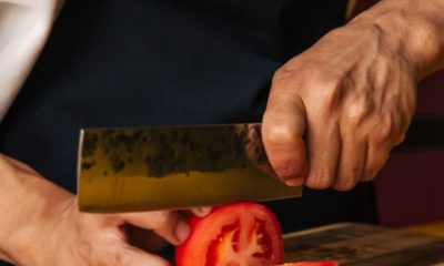 person cutting a tomato with nakiri kitchen knife